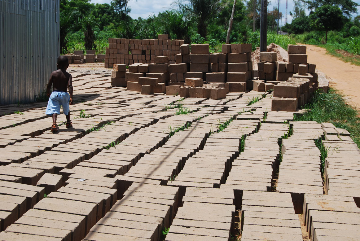 Kind auf Baustelle mit Ziegelsteinen